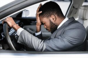 Man in car seeking pain relief from headache