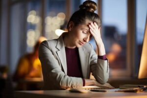 Woman sitting at laptop seeking relief from her tension headache